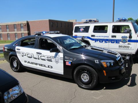 1991 Ford LTD Crown Victoria - Black-and-white Chevrolet Caprice police sedan marked POLICE Fairfield parked beside a white Hartford Police Hummer.