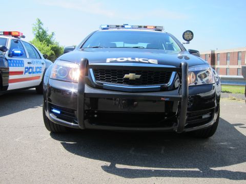 1991 Ford LTD Crown Victoria - Head-on view of a black Chevrolet Caprice police car with a push bumper, POLICE lettered on the hood and activated blue lights.