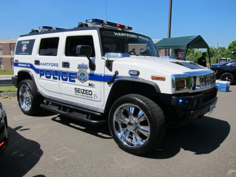1991 Ford LTD Crown Victoria - White and blue Hummer H2 marked HARTFORD POLICE and SEIZED from a drug dealer, on chrome wheels under a clear sky.