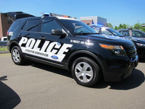 1991 Ford LTD Crown Victoria - Black Ford Explorer police SUV marked POLICE Interceptor Demonstrator and To Protect and To Serve, parked in a lot.