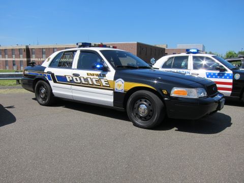 1991 Ford LTD Crown Victoria - Side view of an Enfield Police Ford Crown Victoria cruiser with roof light bar next to other patrol cars.