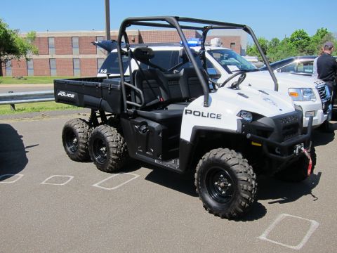 1991 Ford LTD Crown Victoria - white Polaris six-wheeled police utility vehicle marked K-9 with a light bar and cargo bed in a parking lot.