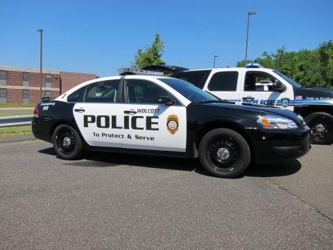 1991 Ford LTD Crown Victoria - black-and-white Wolcott Police Chevrolet Impala cruiser reading To Protect and Serve parked by other units.