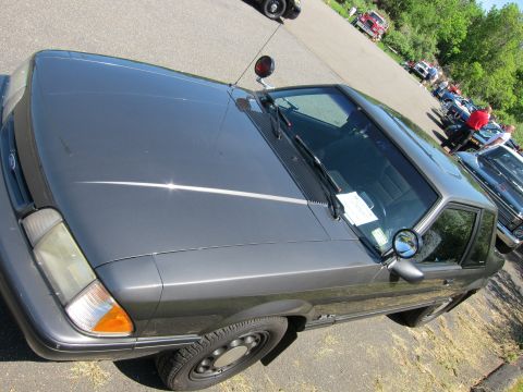 1991 Ford LTD Crown Victoria - High-angle front view of a gray Ford Mustang fox-body coupe with hood and windshield showing in a parking lot.