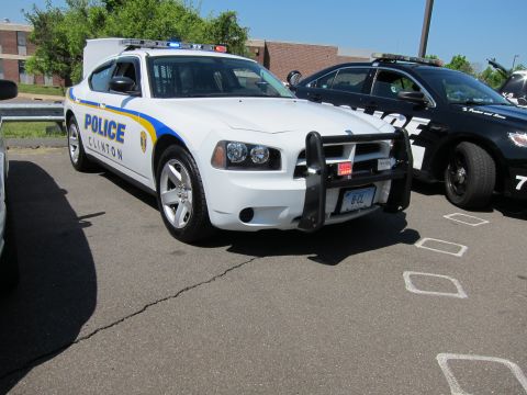 1991 Ford LTD Crown Victoria - white Clinton Police Dodge Charger with brush guard and roof light bar parked beside a black police sedan.