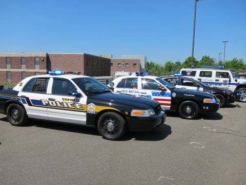 1991 Ford LTD Crown Victoria - row of black-and-white police sedans with roof light bars parked in a lot, Enfield and New Britain markings visible.