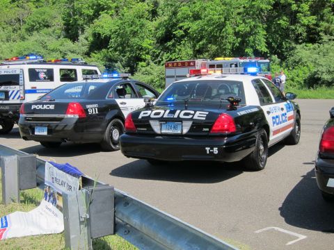 1991 Ford LTD Crown Victoria - Two black-and-white POLICE Ford Crown Victoria cruisers parked at angles with a red fire engine behind them.