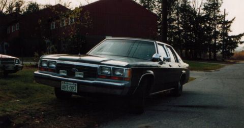 1991 Ford LTD Crown Victoria - A dark 1991 Ford Crown Victoria LTD is parked on a street next to a house.