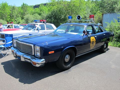 1991 Ford LTD Crown Victoria - dark blue full-size police sedan with chrome bumpers, a roof-mounted siren and lightbar, and a circular door emblem.