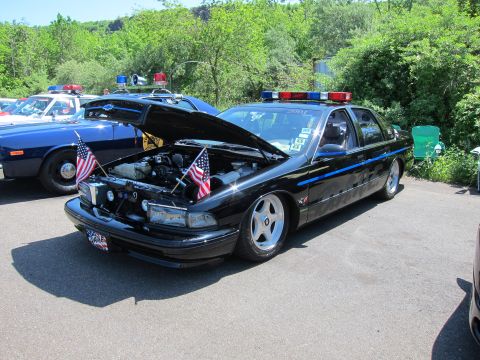 1991 Ford LTD Crown Victoria - black police-style sedan with its hood open showing the engine, small American flags mounted, and a roof lightbar.