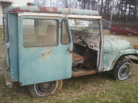 1978 Ford Bronco - This weathered Jeep panel van sits in a grassy lot, showing signs of age and disuse.