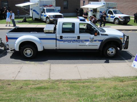 1991 Ford LTD Crown Victoria - white Ford crew-cab pickup lettered HARTFORD POLICE TRAFFIC DIVISION with blue stripes parked at a curb.