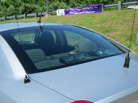 1991 Ford LTD Crown Victoria - Close-up of a silver car's rear window with twin whip antennas and equipment visible on the rear deck and seat.