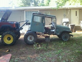 1978 Ford Bronco - A custom-built vehicle with a cab sits next to a lifted Jeep Cherokee in a yard.