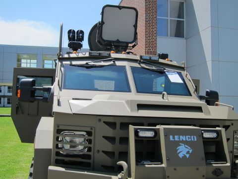 1991 Ford LTD Crown Victoria - Close front view of a tan Lenco armored vehicle showing the windshield, roof optics screen and Lenco grille badge.