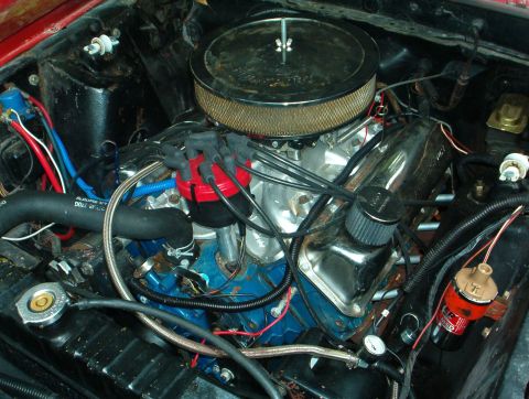 1978 Ford Bronco - Engine bay view of a blue-painted Ford V8 in a red-bodied car, topped with an aluminum intake manifold, black round chrome-lipped air clean…