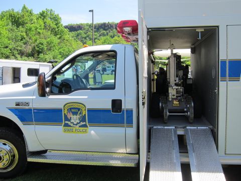 1991 Ford LTD Crown Victoria - white Ford F-550 Connecticut State Police bomb-squad truck with open rear bay revealing a tracked EOD robot on a ramp.