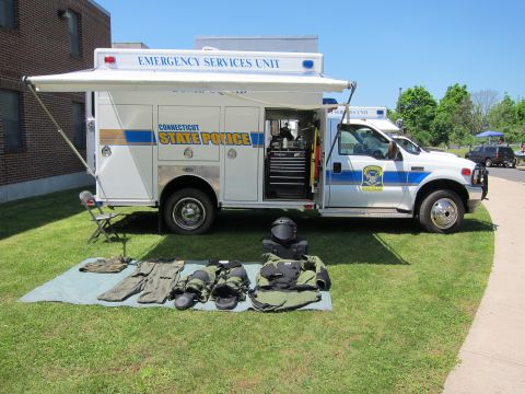 1991 Ford LTD Crown Victoria - white Connecticut State Police Emergency Services Unit truck with helmet and tactical gear displayed on a tarp on the grass.