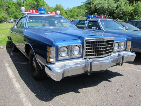 1991 Ford LTD Crown Victoria - Front three-quarter view of a dark-blue 1970s Ford State Police sedan with chrome bumper, roof beacons and State Police sign.