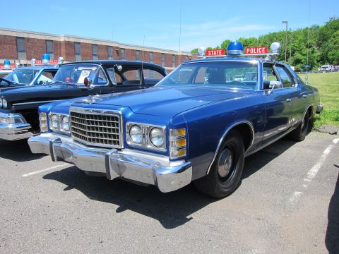 1991 Ford LTD Crown Victoria - blue 1970s Ford full-size sedan lettered STATE POLICE with red dome and roof bar lights parked at an outdoor police-car show.