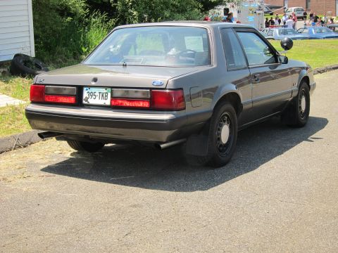 1991 Ford LTD Crown Victoria - Gray Fox-body Ford Mustang notchback coupe seen from the rear three-quarter with plate 395-TKB parked at a curb.