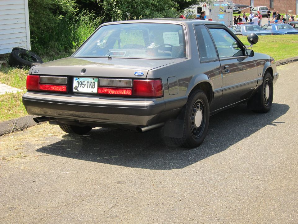 Gray Fox-body Ford Mustang LX sedan, rear three-quarter view at curb