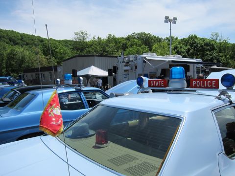 1991 Ford LTD Crown Victoria - Close view of several light-blue State Police cars showing their dome lights, red beacons, and a small flag under a clear sky.