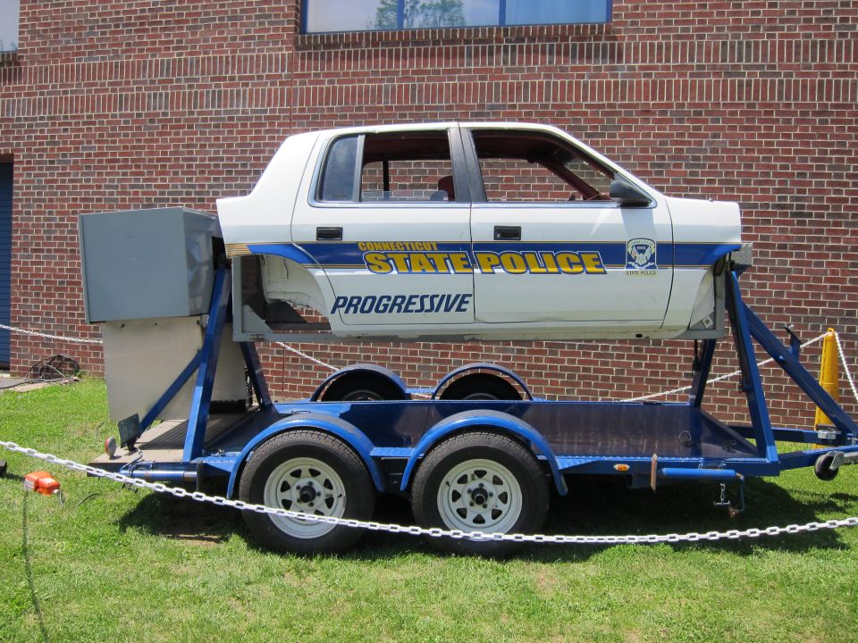 Connecticut State Police rollover car shell on blue trailer with Progressive decal