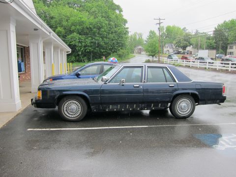 1991 Ford Crown Victoria LTD - A 1991 Ford Crown Victoria LTD is seen parked on a wet day, with another vehicle beside it.