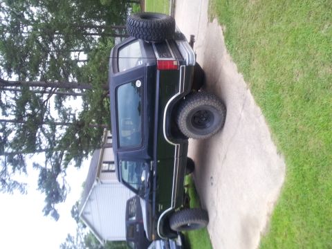 1986 Ford Bronco - This black SUV, likely a 1980s model, is viewed from the front-three-quarter angle with a spare tire mounted on its rear.