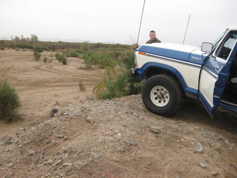 1979 Ford Bronco - A blue and white 1979 Ford Bronco sits on a dirt embankment in a dry, brushy landscape.