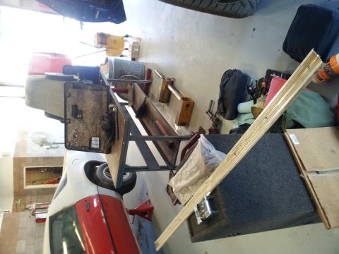 1979 Ford Bronco - A car door panel and other parts are laid out on a workbench in a cluttered garage setting.