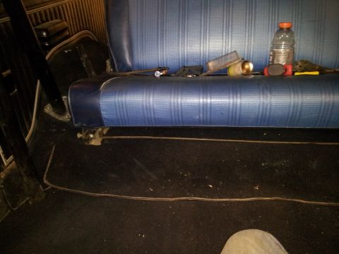 1979 Ford Bronco - The interior of a vehicle shows a blue patterned seat with items scattered on top.