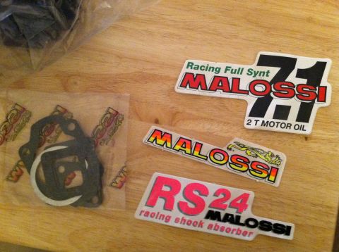 1981 Garelli Rally Sport - Various Malossi branded stickers and a set of gaskets are laid out on a wooden surface.