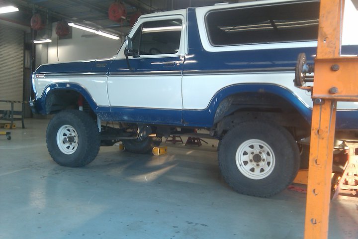 Blue and white Ford Bronco on lifts in a garage