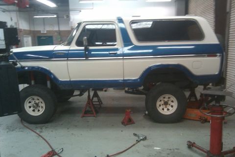 1979 Ford Bronco - Ford Bronco undergoing repairs, lifted on jack stands in a workshop.