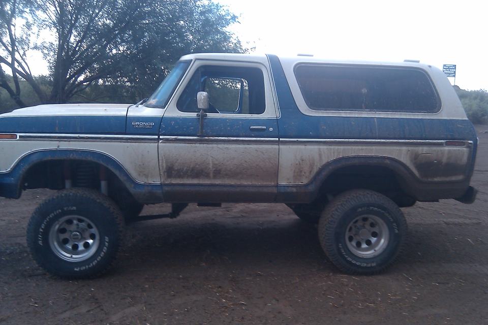 Two-tone blue and white 1978 Ford Bronco, side view, lifted, dirty