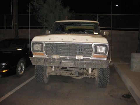 1979 Ford Bronco - Frontal view of a 1977 Ford F-Series truck, parked beside another vehicle at night.