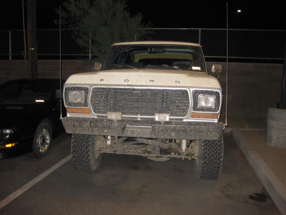 Front view of a 1977 Ford F-Series truck parked next to a black car