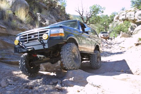 1994 Ford Bronco - Modified 1994 Ford Bronco navigates a challenging rocky terrain with another vehicle following behind.