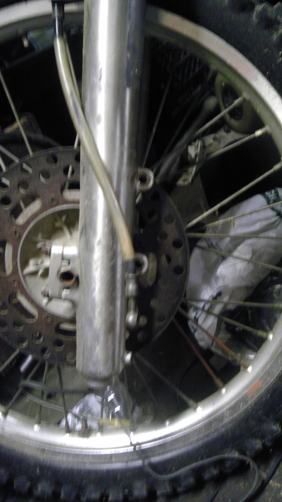 Close-up of a motorcycle's front wheel, brake disc, and suspension fork