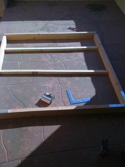 1968 Ford Mustang - A wooden frame is under construction on a tiled patio, with tools like a tape measure and corner braces nearby.