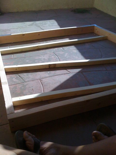 1968 Ford Mustang - A wooden frame is assembled on a patio, with shadows indicating a sunny day.