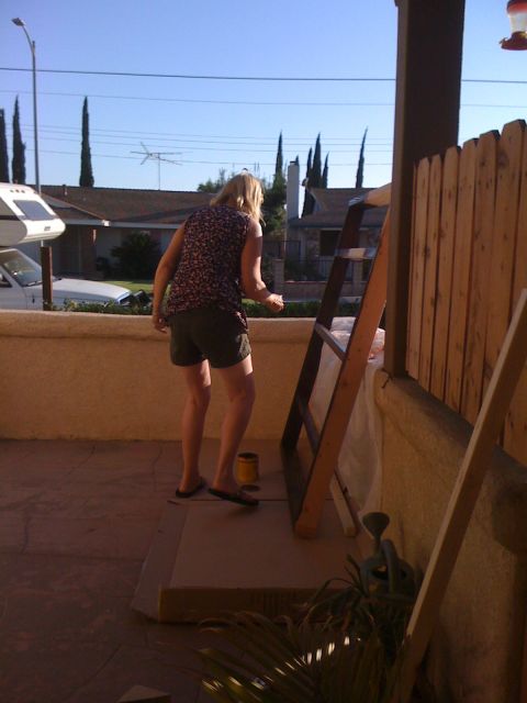 1968 Ford Mustang - A woman is painting a wooden ladder on a porch on a sunny day.