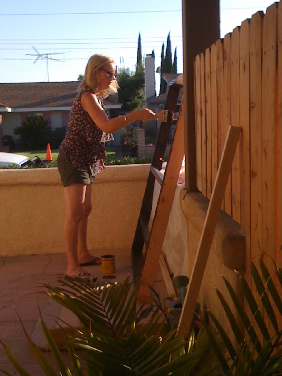 Woman painting a wooden fence on a sunny day