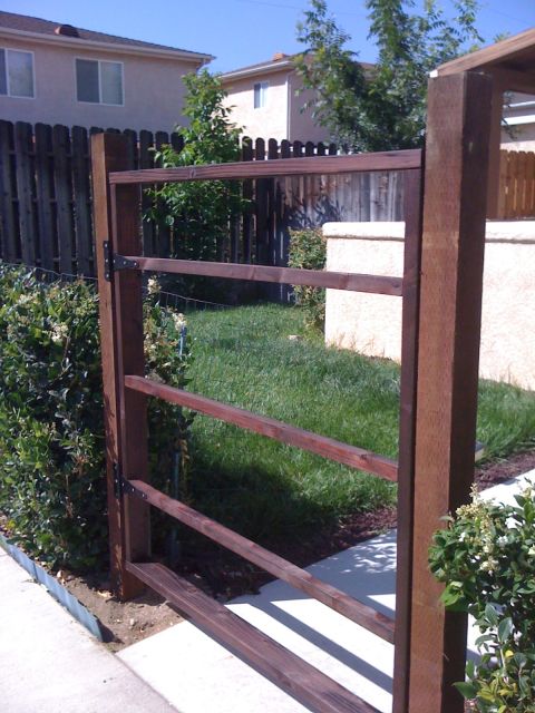 1968 Ford Mustang - A wooden fence gate stands open in a residential backyard, leading to a grassy area.