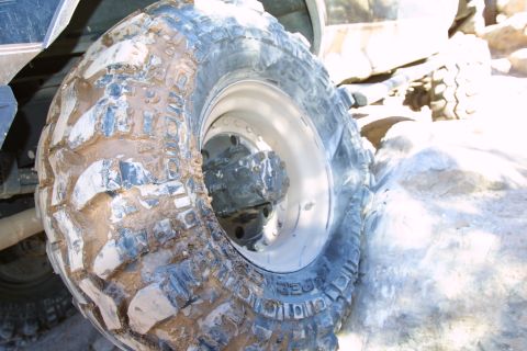 1994 Ford Bronco - Close-up of a heavily muddied off-road tire and wheel assembly.