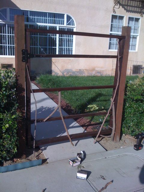 1968 Ford Mustang - A partially constructed metal gate stands in front of a house with barred windows.
