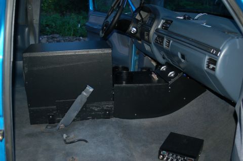 1992 Ford F-150 - The interior of a truck features a custom console and a large subwoofer box, obscuring the original dashboard layout.