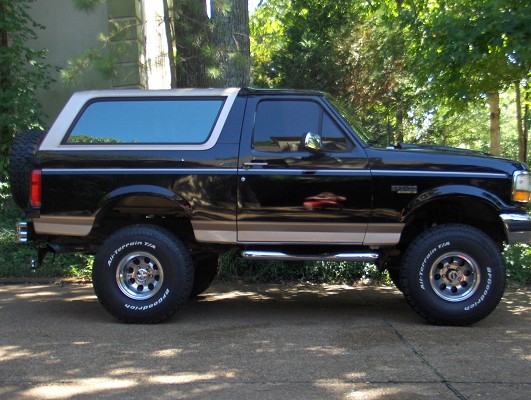 Black Ford Bronco with tan stripe, lifted on BFGoodrich all-terrains, passenger-side view